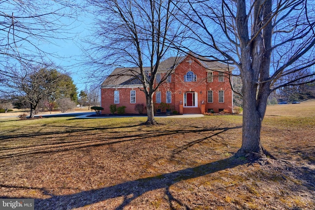 view of front facade with a front yard, crawl space, and brick siding