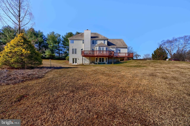 back of house with a deck, a yard, and a chimney