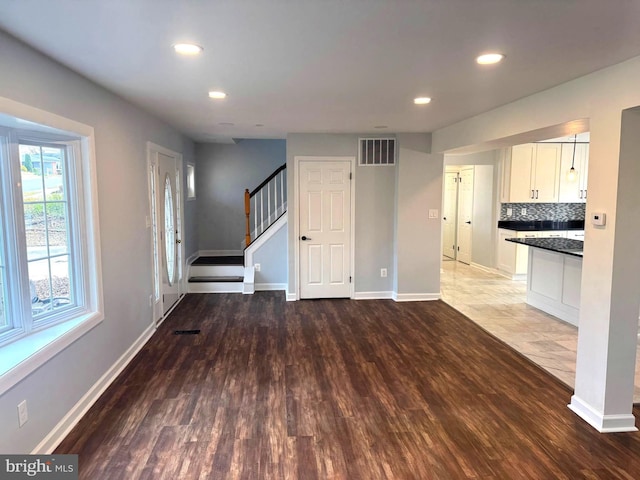 unfurnished living room with recessed lighting, wood finished floors, visible vents, baseboards, and stairs