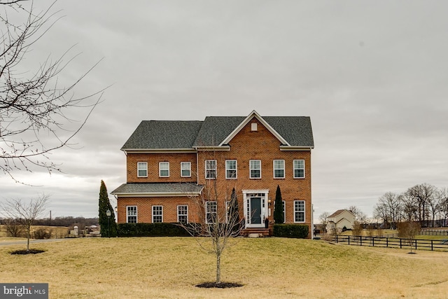 view of front of property featuring brick siding, a front lawn, and fence