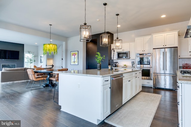 kitchen with tasteful backsplash, white cabinets, appliances with stainless steel finishes, and dark wood-type flooring