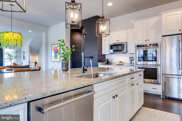 kitchen with dark wood-type flooring, a sink, tasteful backsplash, appliances with stainless steel finishes, and white cabinets