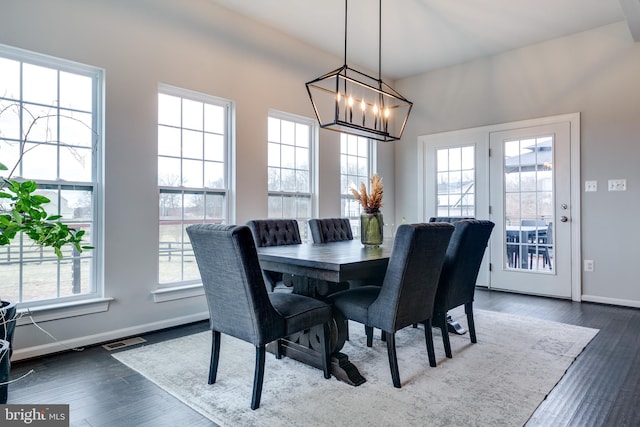 dining space featuring dark wood finished floors, visible vents, a chandelier, and baseboards