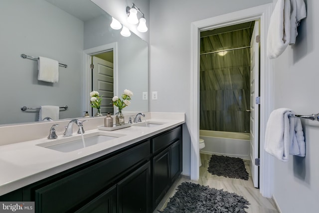 bathroom featuring bathtub / shower combination, double vanity, toilet, and a sink