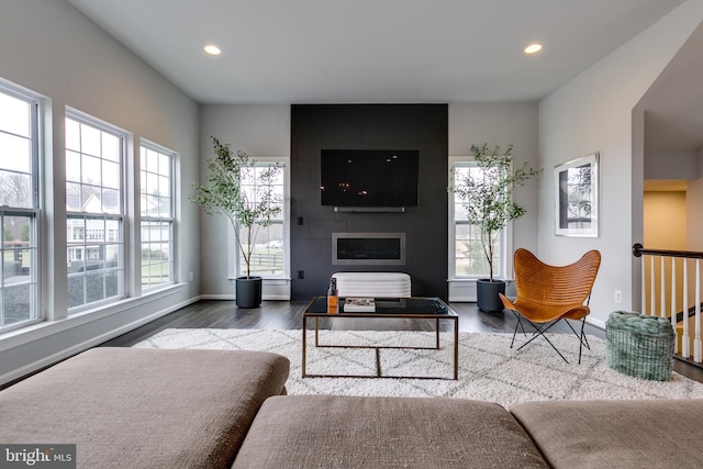 living area with recessed lighting, baseboards, a large fireplace, and wood finished floors