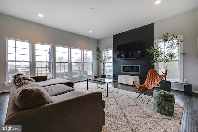 living room with a glass covered fireplace, recessed lighting, wood finished floors, and a wealth of natural light