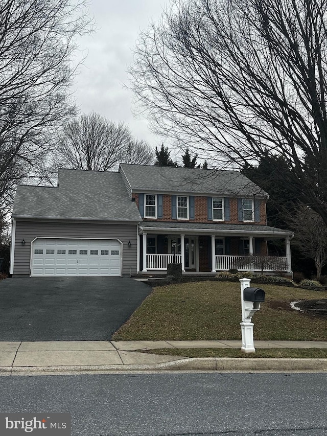 view of front of property with aphalt driveway, a garage, covered porch, and a front lawn