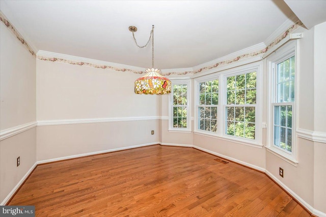 spare room with visible vents, baseboards, wood finished floors, and ornamental molding