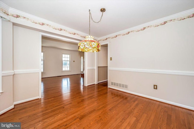 spare room featuring visible vents, ornamental molding, baseboards, and wood finished floors