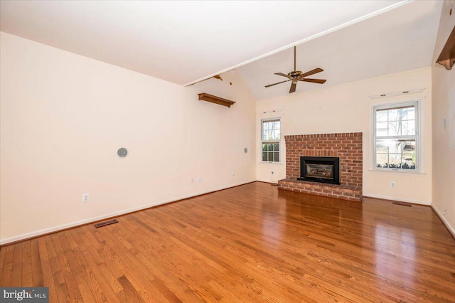 unfurnished living room featuring visible vents, lofted ceiling, wood finished floors, a fireplace, and baseboards