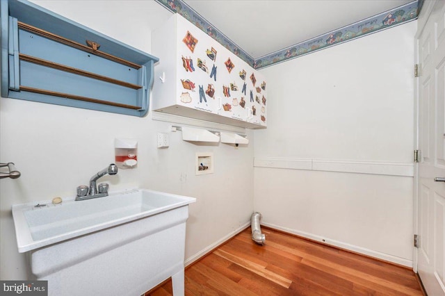 clothes washing area featuring a sink, wood finished floors, baseboards, hookup for a washing machine, and laundry area