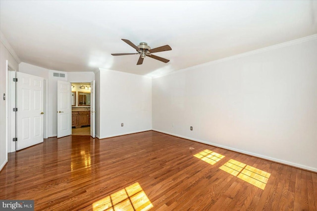 empty room featuring visible vents, a ceiling fan, wood finished floors, crown molding, and baseboards