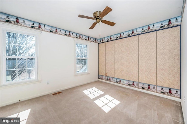 empty room featuring visible vents, baseboards, carpet, and a ceiling fan