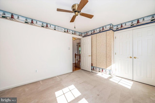 unfurnished bedroom with wallpapered walls, baseboards, carpet, and a ceiling fan