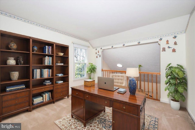 office space featuring baseboards, light carpet, and lofted ceiling