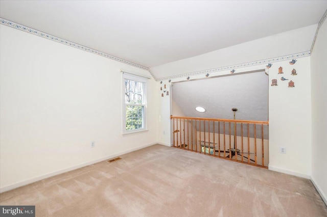 spare room featuring visible vents, baseboards, carpet, and lofted ceiling