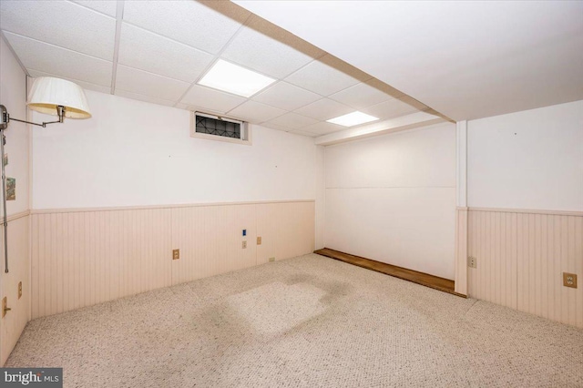 finished basement featuring a drop ceiling, wainscoting, visible vents, and carpet floors