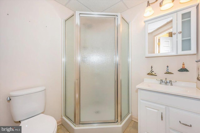 full bathroom with a stall shower, toilet, vanity, and a paneled ceiling