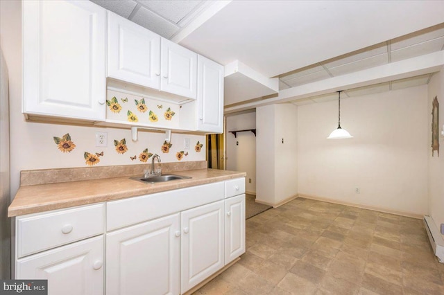 kitchen with light countertops, white cabinets, decorative light fixtures, and a sink