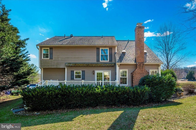 rear view of property featuring a yard and a chimney