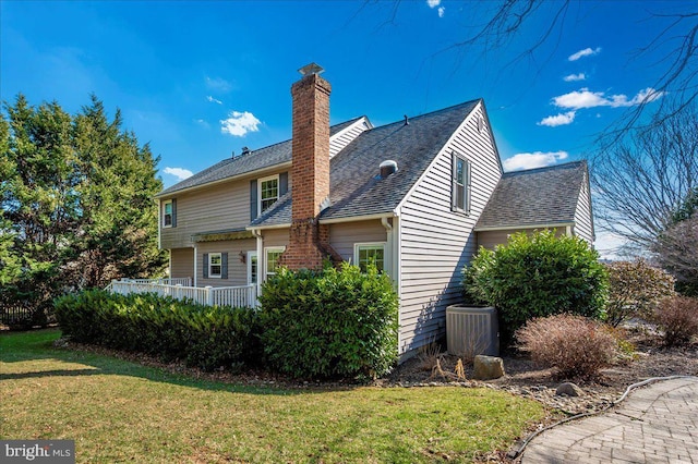 view of property exterior with a shingled roof, a lawn, central AC, and a chimney