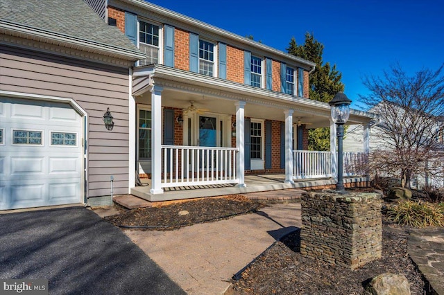 view of front facade featuring brick siding, covered porch, and an attached garage