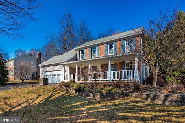 colonial-style house with a front yard, driveway, a porch, an attached garage, and brick siding