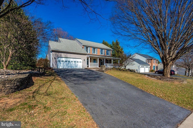 view of front of house with a garage, driveway, a porch, and a front yard