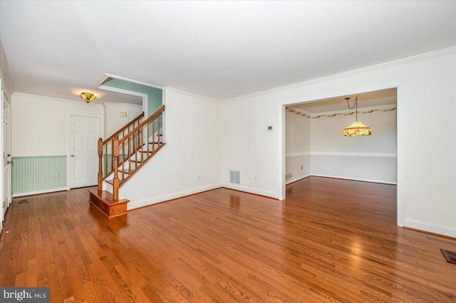 spare room with visible vents, ornamental molding, stairs, and wood finished floors