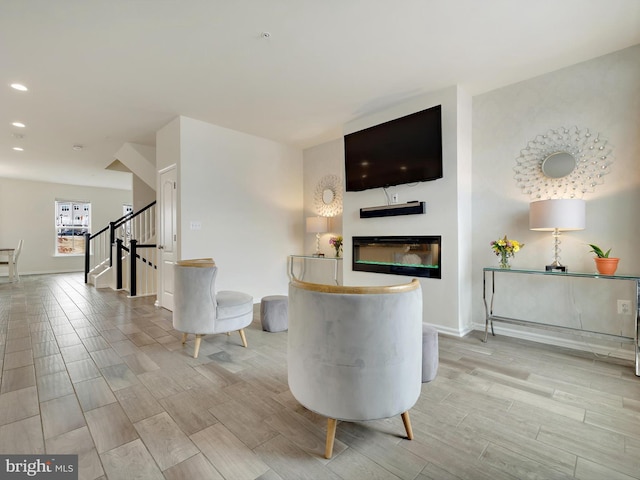 interior space featuring baseboards, stairway, wood finish floors, and a glass covered fireplace