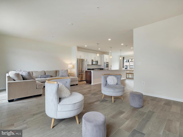 living area with baseboards, wood finish floors, and recessed lighting