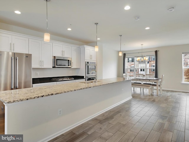 kitchen with an island with sink, appliances with stainless steel finishes, white cabinets, and recessed lighting