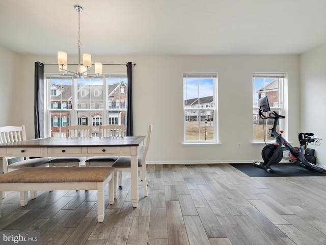 dining room with a notable chandelier, baseboards, and wood finished floors