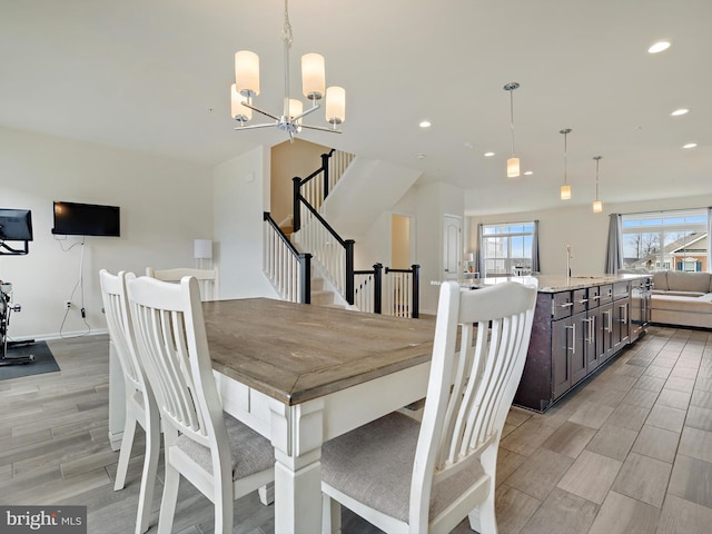 dining area featuring a notable chandelier, recessed lighting, wood tiled floor, baseboards, and stairs