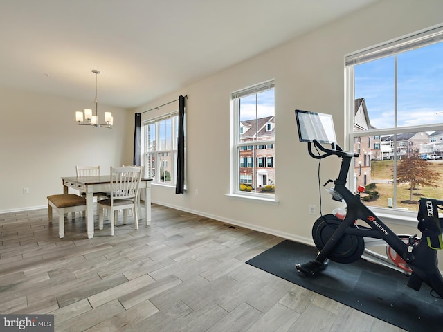 exercise room with a chandelier, wood finished floors, and baseboards