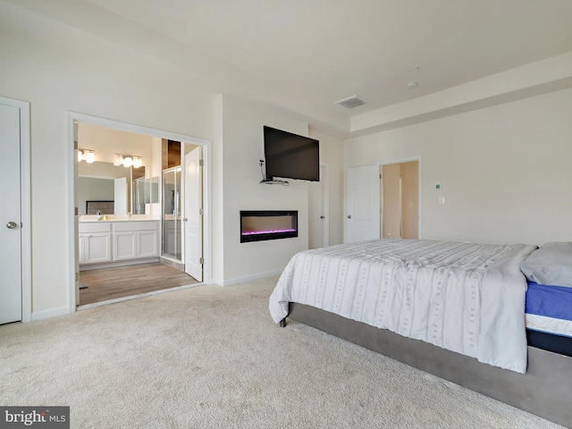 bedroom with ensuite bath, carpet, visible vents, and baseboards