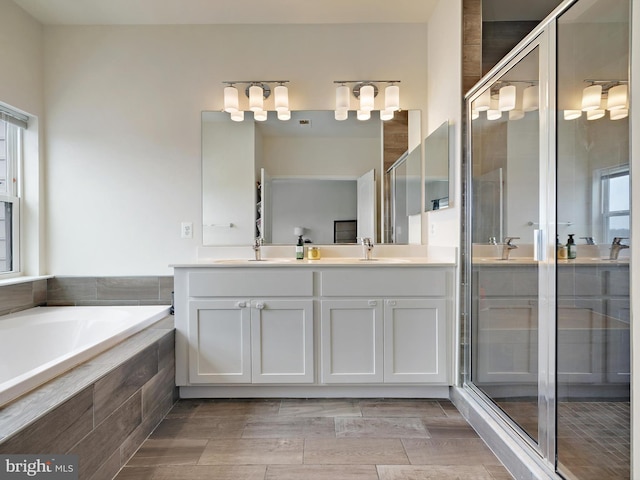 bathroom with a sink, a shower stall, a bath, and double vanity