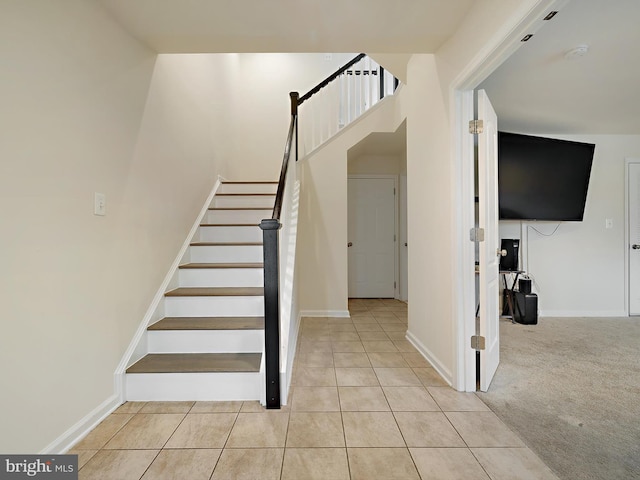 staircase featuring baseboards, carpet flooring, and tile patterned floors