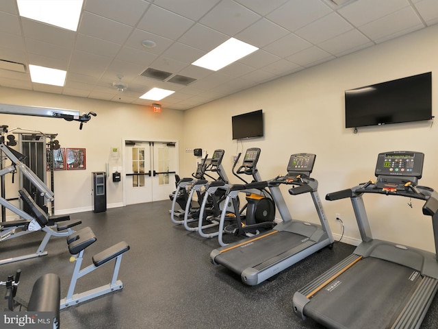 exercise room with a drop ceiling, visible vents, and baseboards