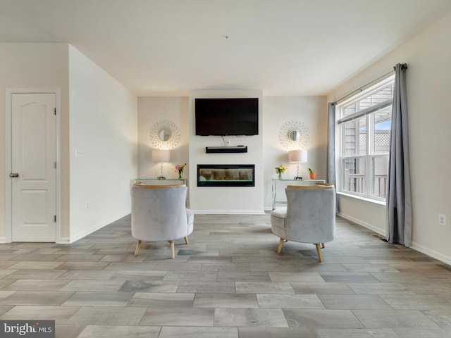 unfurnished room with baseboards, a glass covered fireplace, and wood tiled floor