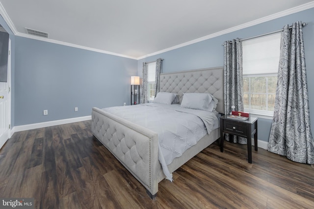 bedroom with baseboards, wood finished floors, visible vents, and crown molding