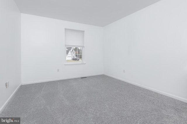 spare room featuring baseboards and carpet flooring