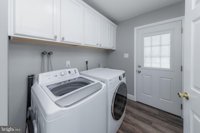 clothes washing area featuring dark wood-style floors, washing machine and dryer, and cabinet space