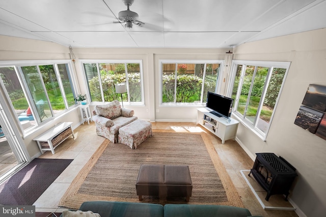 sunroom featuring a wood stove, tile patterned flooring, and a wall unit AC