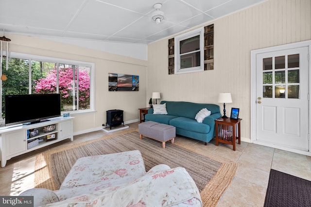 living room with a wood stove, tile patterned floors, and baseboards