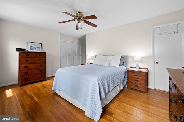 bedroom with a closet, a ceiling fan, light wood-style flooring, and baseboards