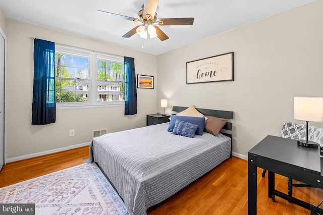 bedroom featuring wood finished floors, visible vents, a ceiling fan, and baseboards