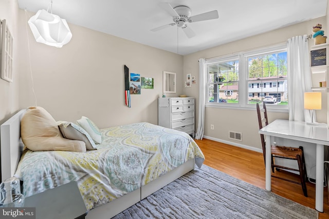bedroom with wood finished floors, visible vents, ceiling fan, and baseboards