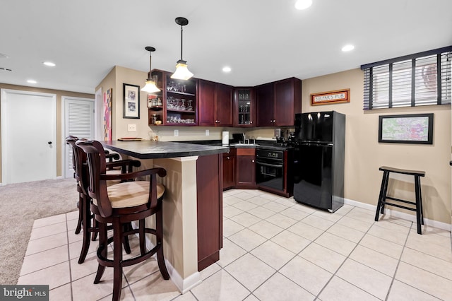 kitchen with a breakfast bar area, dark countertops, black appliances, recessed lighting, and a peninsula