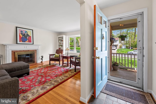 entryway featuring a fireplace, wood finished floors, plenty of natural light, and baseboards
